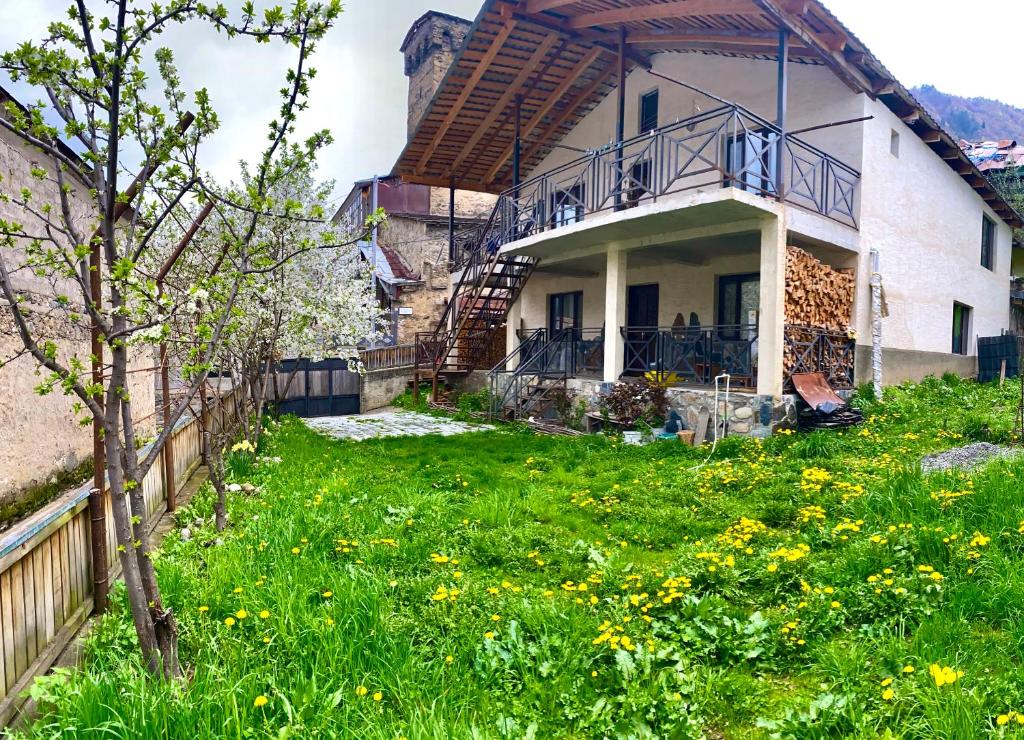 una casa con un patio con flores amarillas en GUEST HOUSE ,, MEMORY'', en Mestia
