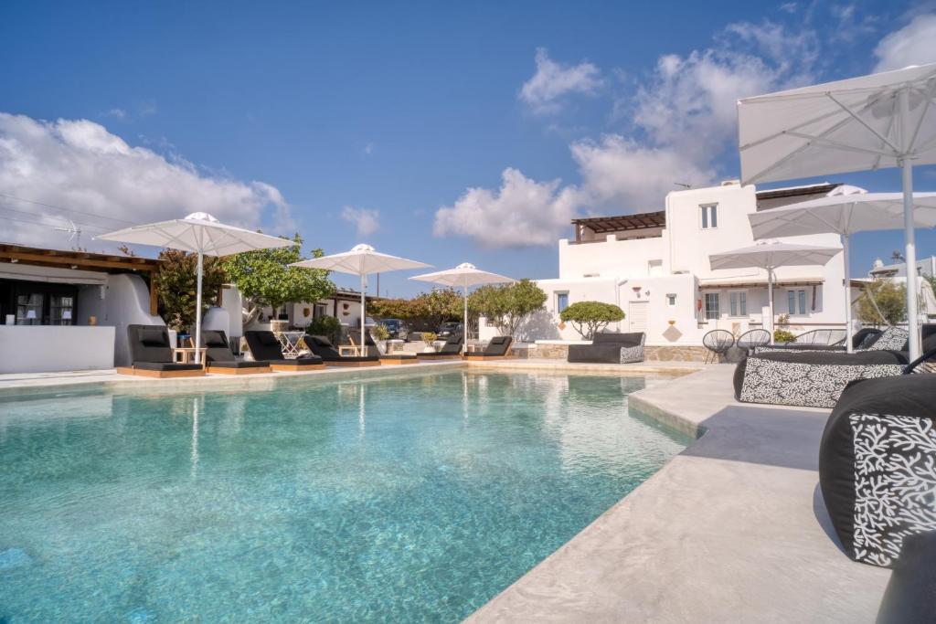 a pool with chairs and umbrellas next to a building at Mykonos Eight in Mikonos