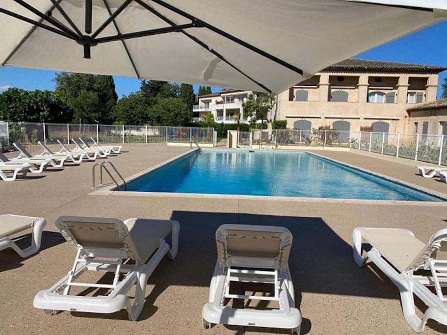 a swimming pool with lounge chairs and an umbrella at Côte d’Azur- Appartement Les Suites de Robinson in Mandelieu-la-Napoule