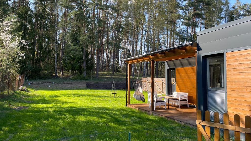 Una cabaña con porche y columpio en un patio. en Kwiat Jabłonki, en Wikno