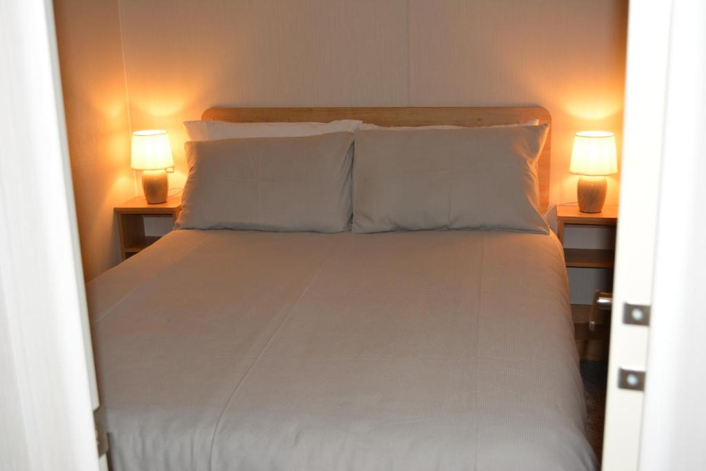 een bed met witte lakens en kussens in een slaapkamer bij Holiday Home at Cherry Tree Holiday Park 738 in Great Yarmouth