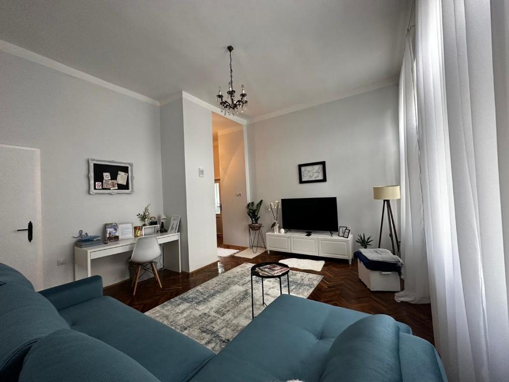 a living room with a blue couch and a tv at Pure of joy City Centre Apartment in Subotica
