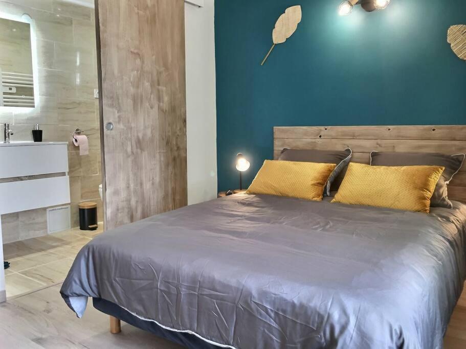 a bedroom with a large bed and a blue wall at Bleu Lavande 1 - Appartement cosy ambiance village in Istres