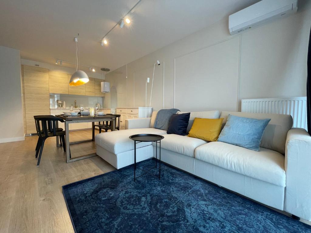 ein Wohnzimmer mit einem weißen Sofa und einem Tisch in der Unterkunft Waveside Apartments and SPA Dziwnów in Dziwnów