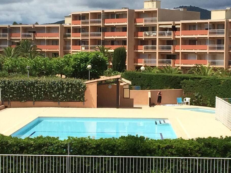 une piscine en face d'un grand immeuble dans l'établissement studio cabine quatre couchages classé 2 étoiles, à Bormes-les-Mimosas