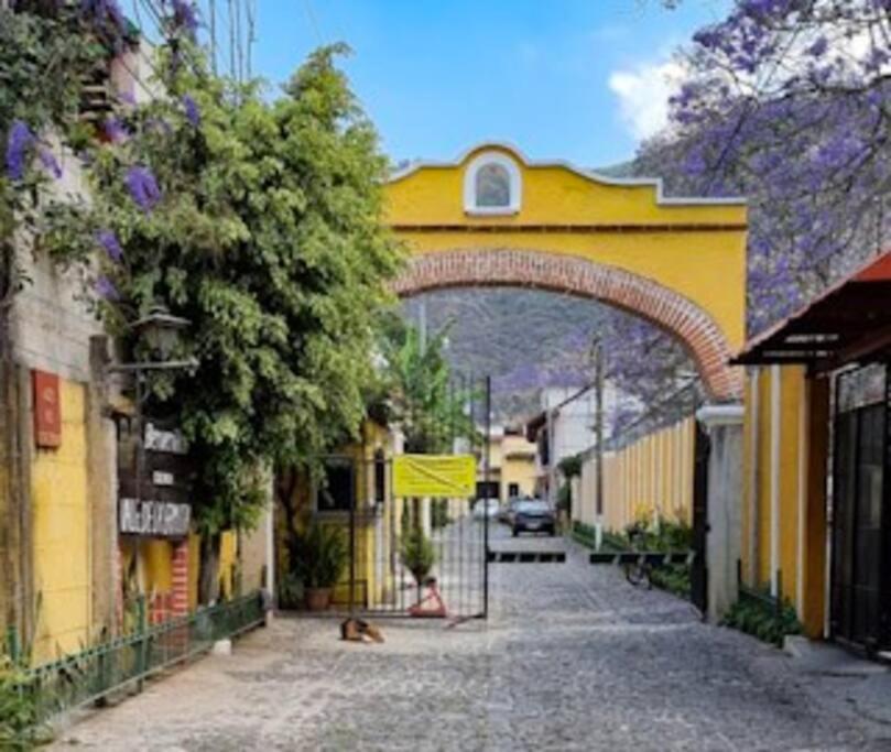 a yellow building with an arch in a street at Casa la Ermita in Antigua Guatemala