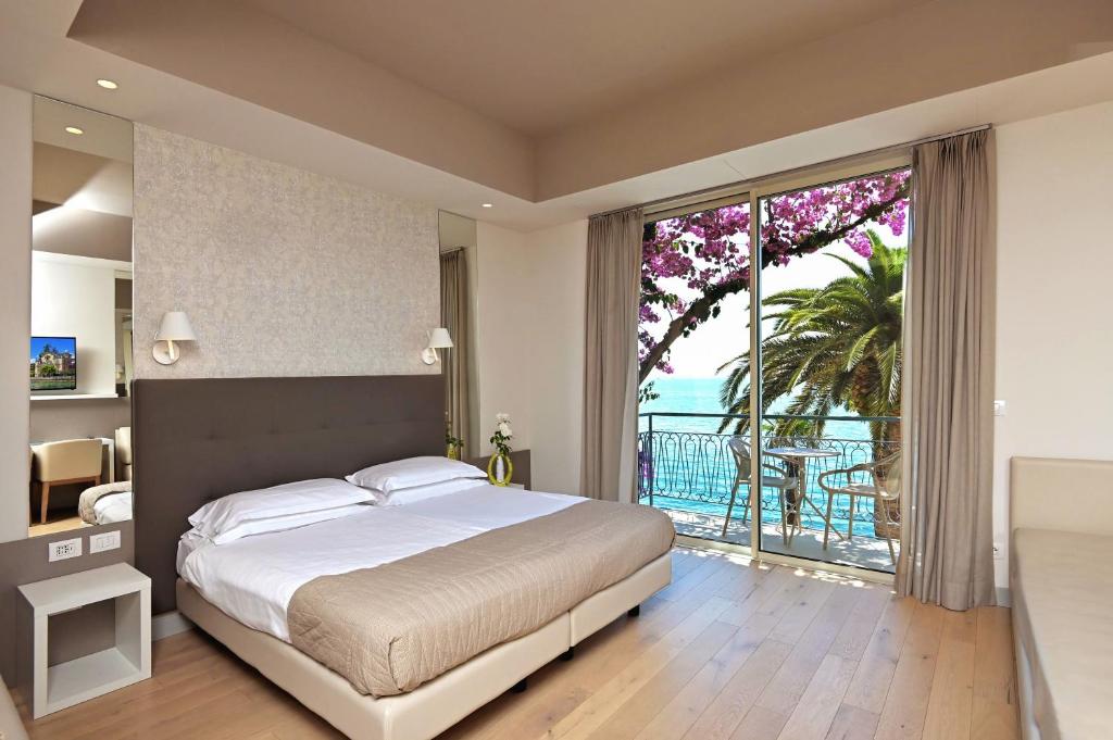 ein Schlafzimmer mit einem großen Bett und einem großen Fenster in der Unterkunft Hotel Monte Baldo e Villa Acquarone in Gardone Riviera
