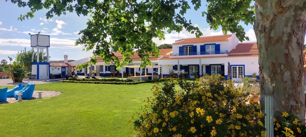 een wit huis met blauwe ramen en een tuin bij Quinta RoSa - Almeirim in Almeirim