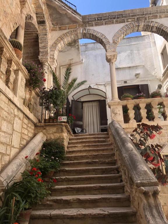 a stone building with stairs leading into a building with flowers at Corte De Ritis in Giovinazzo