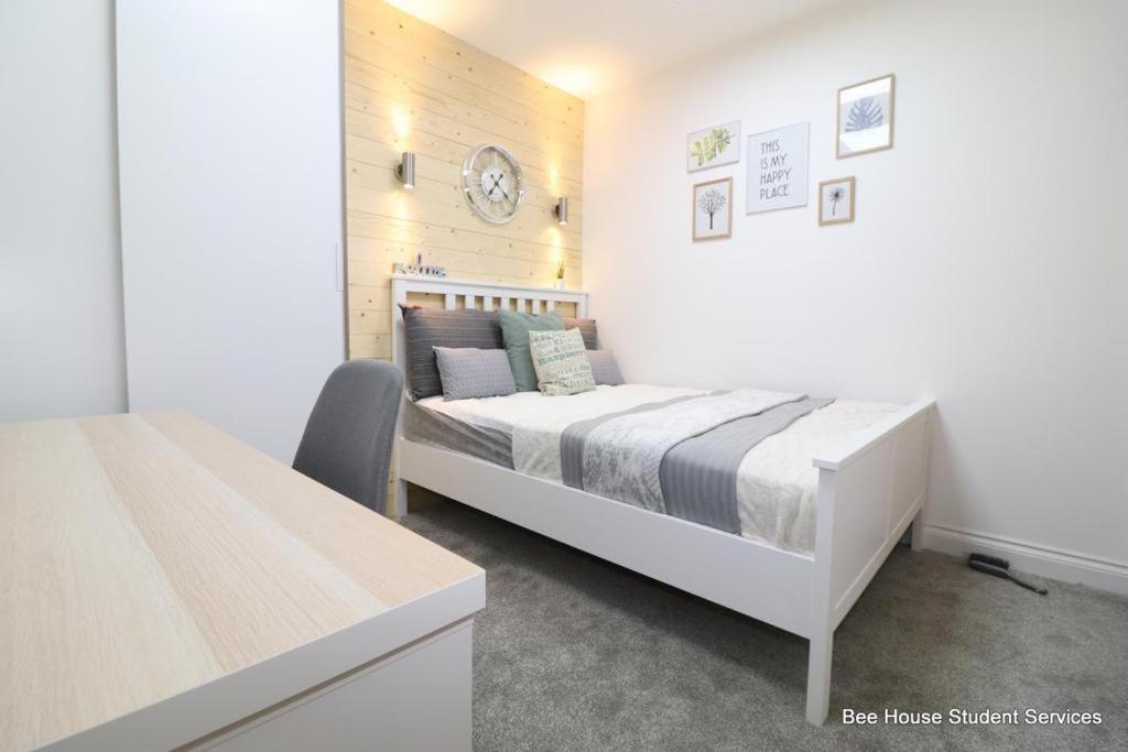 萊斯特的住宿－Leicester City Apartments，白色的卧室配有一张床和墙上的时钟