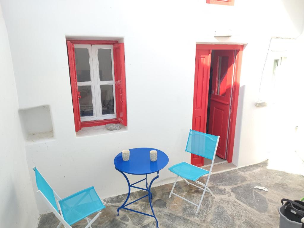 a blue table and chairs in a room with a red door at Perseids Traditional House in Amorgos
