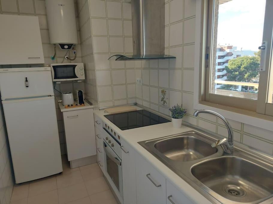 una pequeña cocina con fregadero y nevera. en Apartamentos CT en Salou