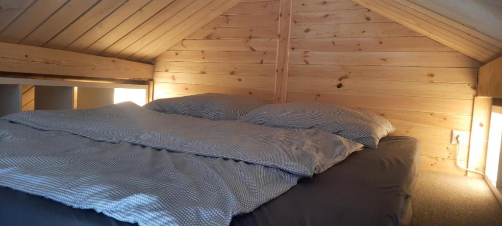 a bed in a room with a wooden wall at Domki Schega in Podamirowo