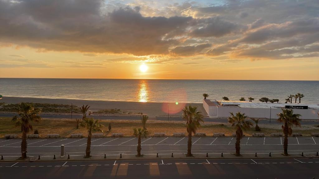 a sunset over the beach with palm trees and a tennis court at SOL Y MAR Location 4 personnes St Cyprien 2 étoiles FNAIM in Saint-Cyprien