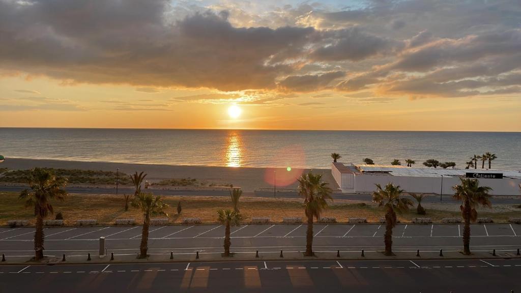 un coucher de soleil sur la plage avec des palmiers et un court de tennis dans l'établissement SOL Y MAR Location 4 personnes St Cyprien 2 étoiles FNAIM, à Saint-Cyprien