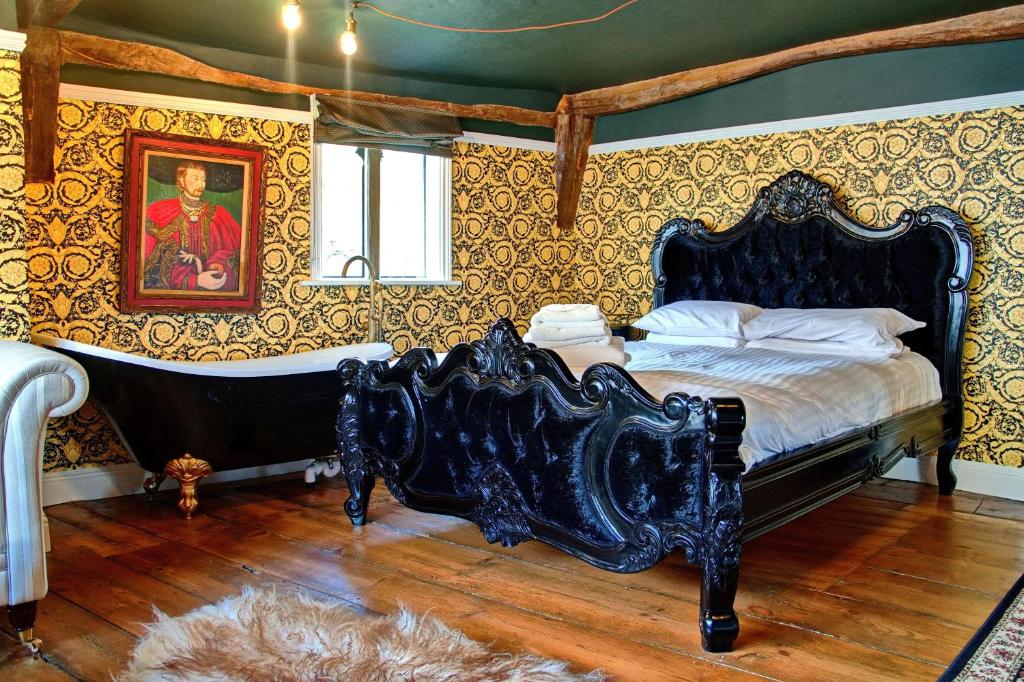 a bedroom with a bed and a tub in it at Huge Deluxe 600 Year Old Essex Manor, Hot Tub, Cinema Room, Sky Tv in Saffron Walden