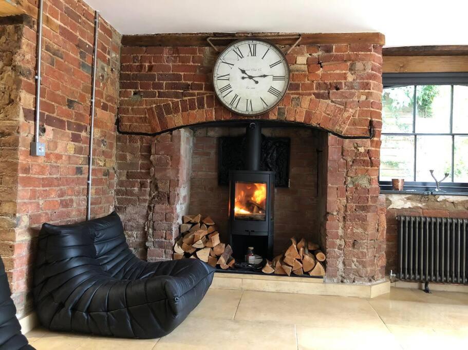 a brick wall with a clock and a fireplace at Lavish Apartment at Montpellier Gardens in Cheltenham