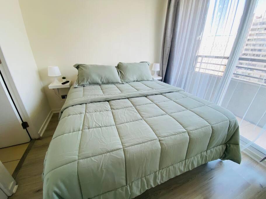 a large bed in a bedroom with a large window at Confortable Apartamento para 3 in Santiago