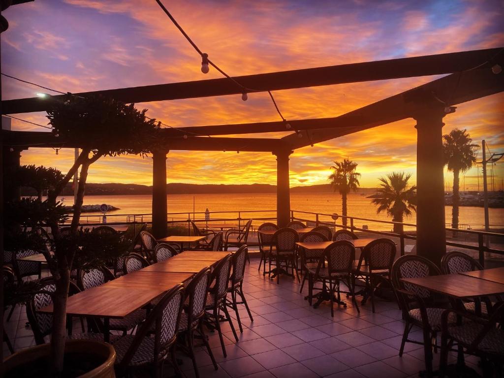 d'une terrasse avec des tables et des chaises et un coucher de soleil en arrière-plan. dans l'établissement Hôtel Les Alizés, à Cavalaire-sur-Mer