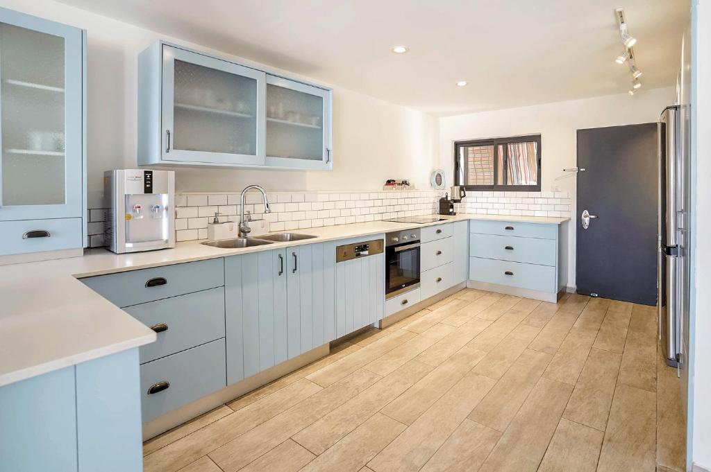 a kitchen with white cabinets and a wooden floor at YalaRent Cliff side villa with private pool in Eilat