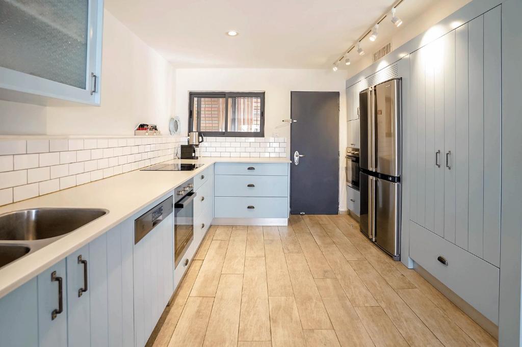 a kitchen with white cabinets and a wooden floor at YalaRent Cliff side villa with private pool in Eilat