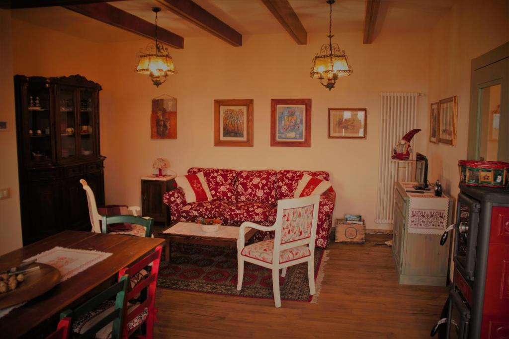 een woonkamer met een rode bank en stoelen bij La Casa di Anna nel Parco delle Dolomiti in Pedavena