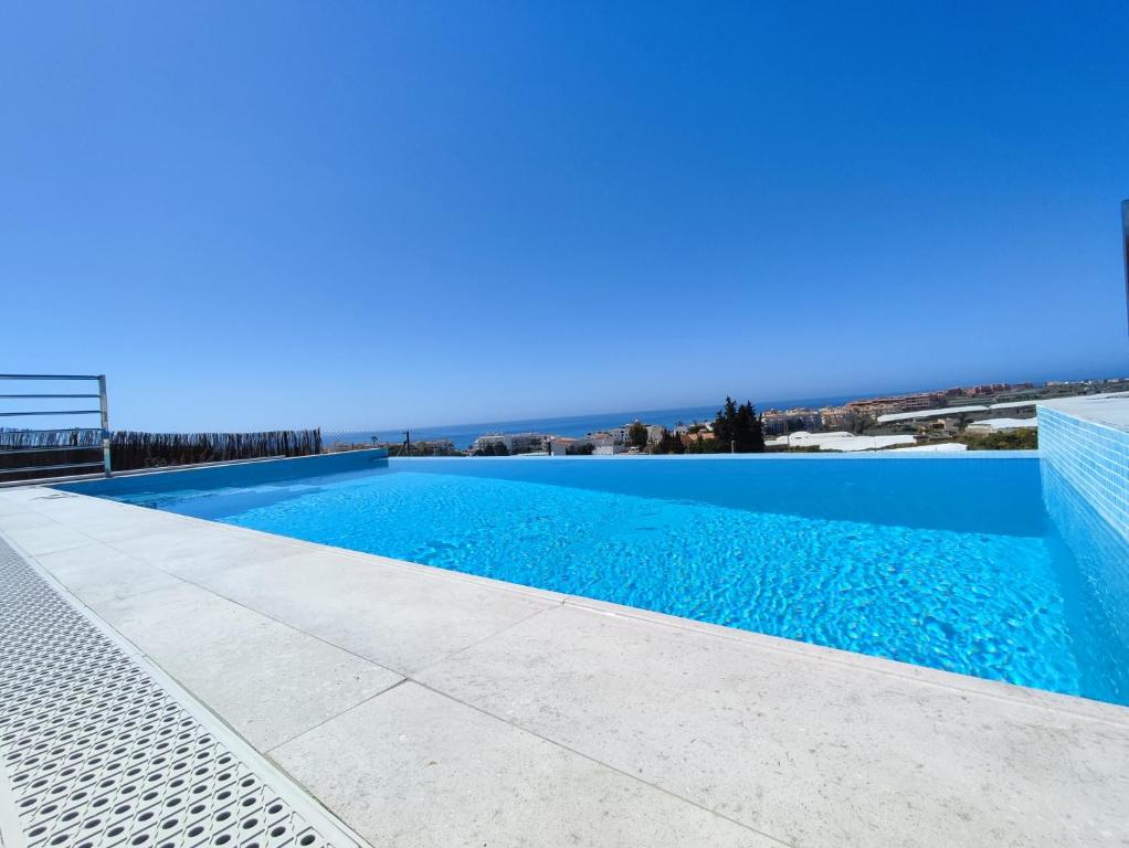 a blue swimming pool with the ocean in the background at Villa Delicia in Torrox
