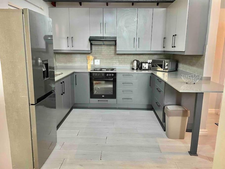 una cocina con electrodomésticos de acero inoxidable y armarios blancos en Separate entry cozy Guesthouse en Hillcrest