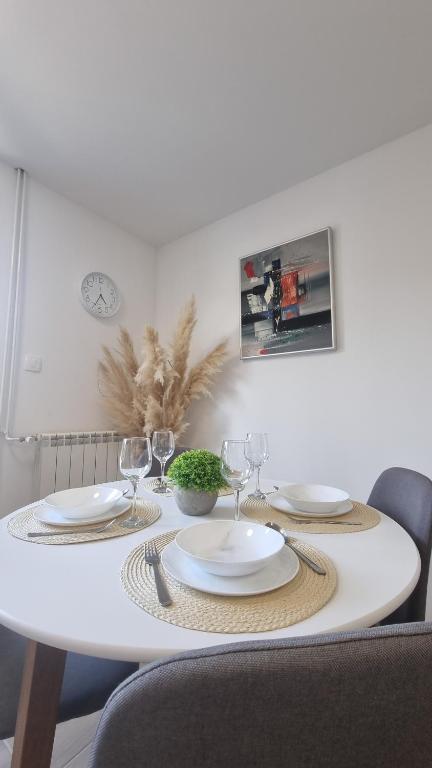 una mesa blanca con platos y copas de vino. en Harmony Apartment Koper, en Koper
