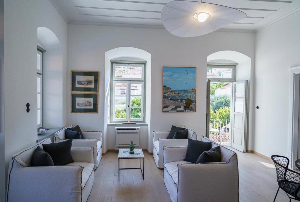 a living room with white furniture and windows at Livin Hydra Private Collection Suite 3 in Hydra