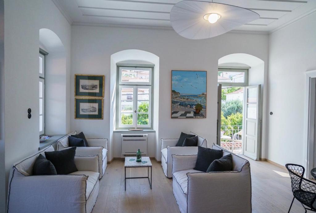 a living room with white furniture and windows at LIVIN Hydra Legacy Suite in Hydra