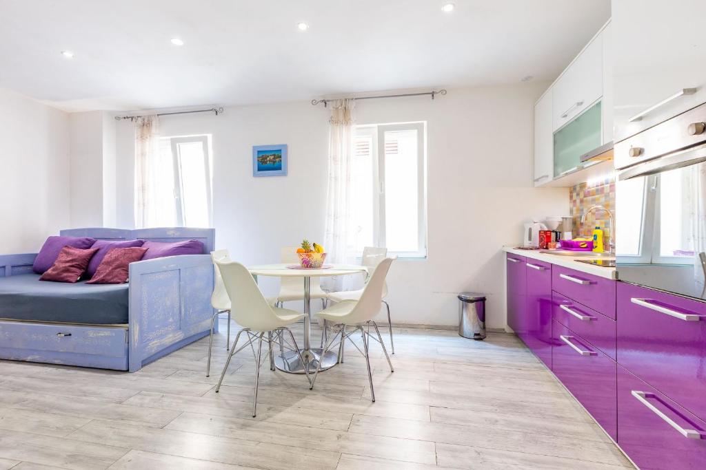 a kitchen with purple cabinets and a table with chairs at Alpha loft 1BR apartment in center in Zadar