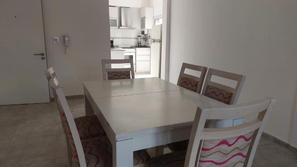 a white dining room table with chairs and a kitchen at Super Departamento amplio y luminoso con cochera in Lanús