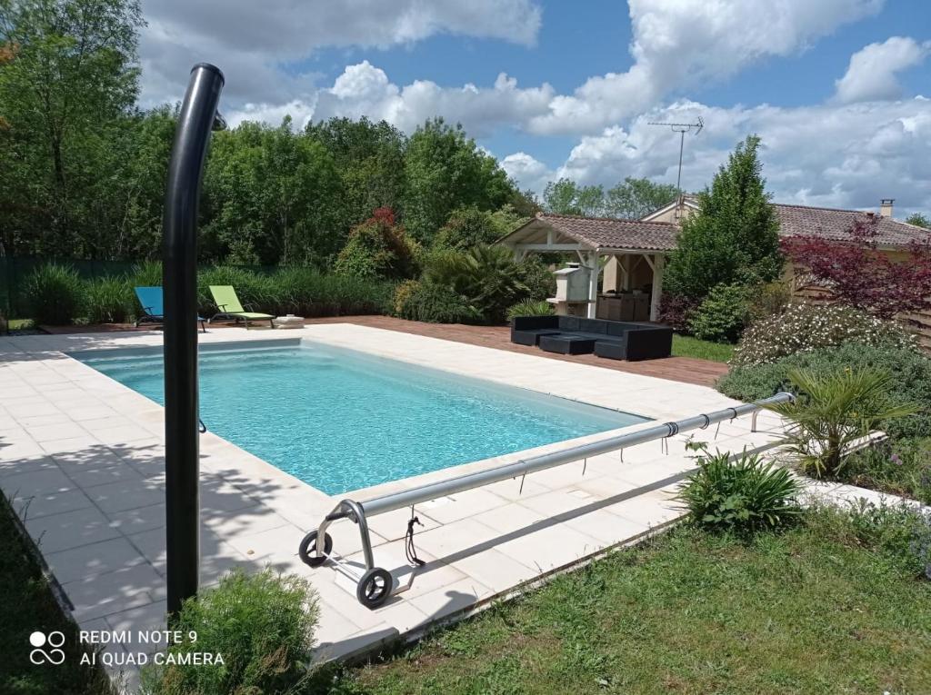 een zwembad in een tuin met een paal ernaast bij Belle maison de vacance avec piscine in Ménesplet