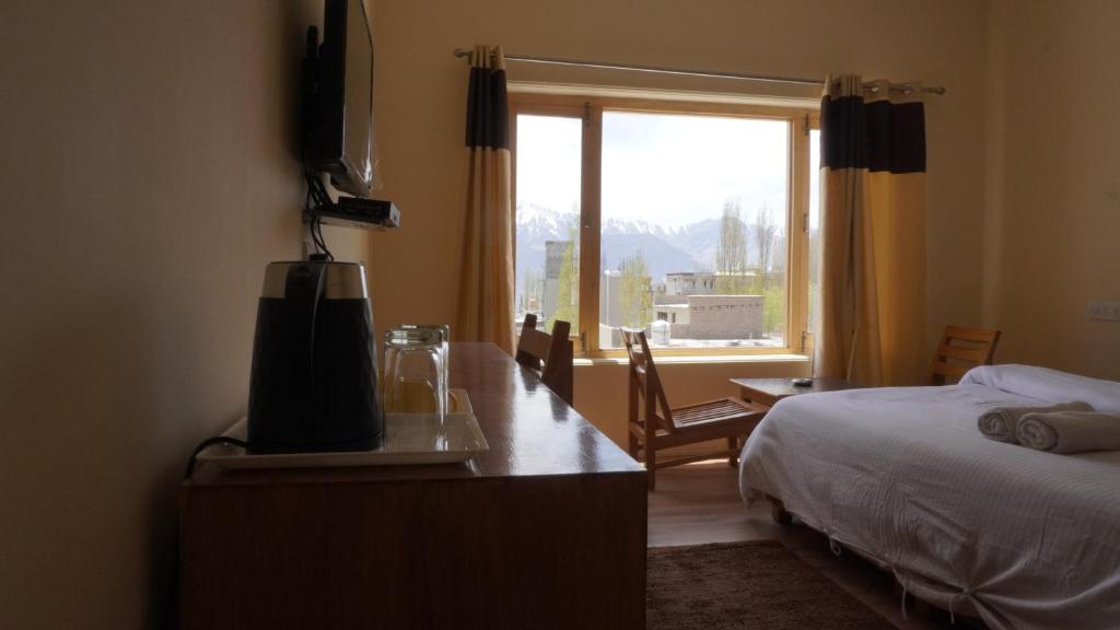 - une chambre avec un lit, une télévision et une fenêtre dans l'établissement 16 ARAHAT GUEST HOUSE, à Leh