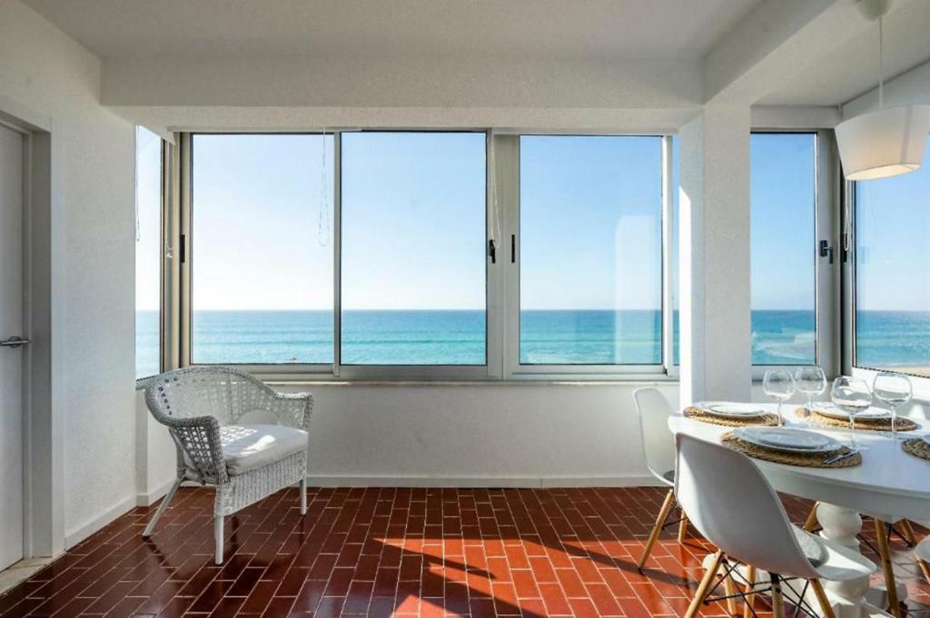 a dining room with a table and chairs and the ocean at Ria Beach House in Faro