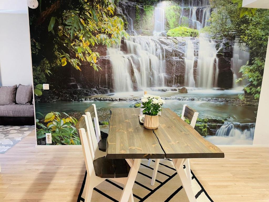 a wooden table in a room with a waterfall mural at Sweet dreams Porvoo in Porvoo