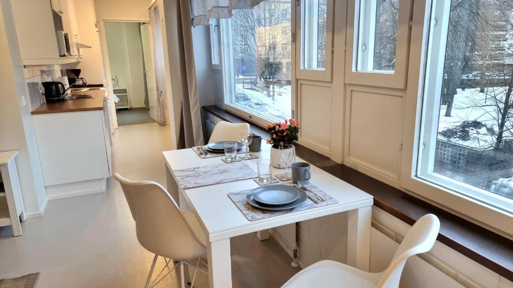 a small white table in a kitchen with windows at Aparthotel Clock 19 in Kotka