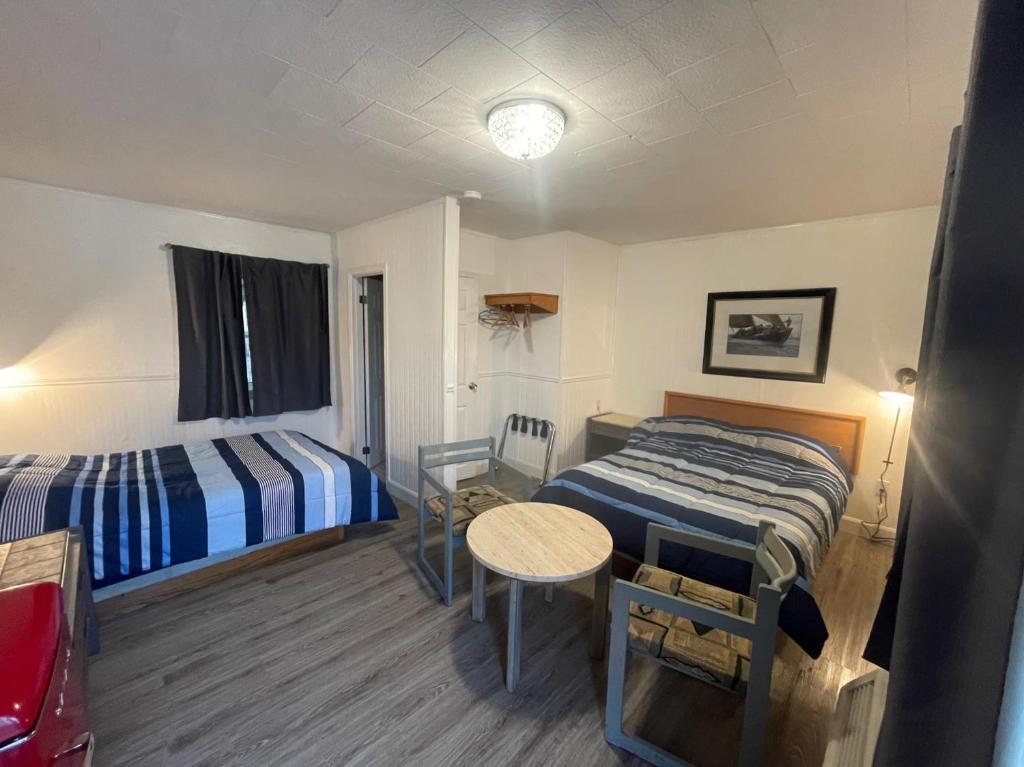 Habitación con 2 camas y mesa. en Cedar Vista Motel, en Tobermory
