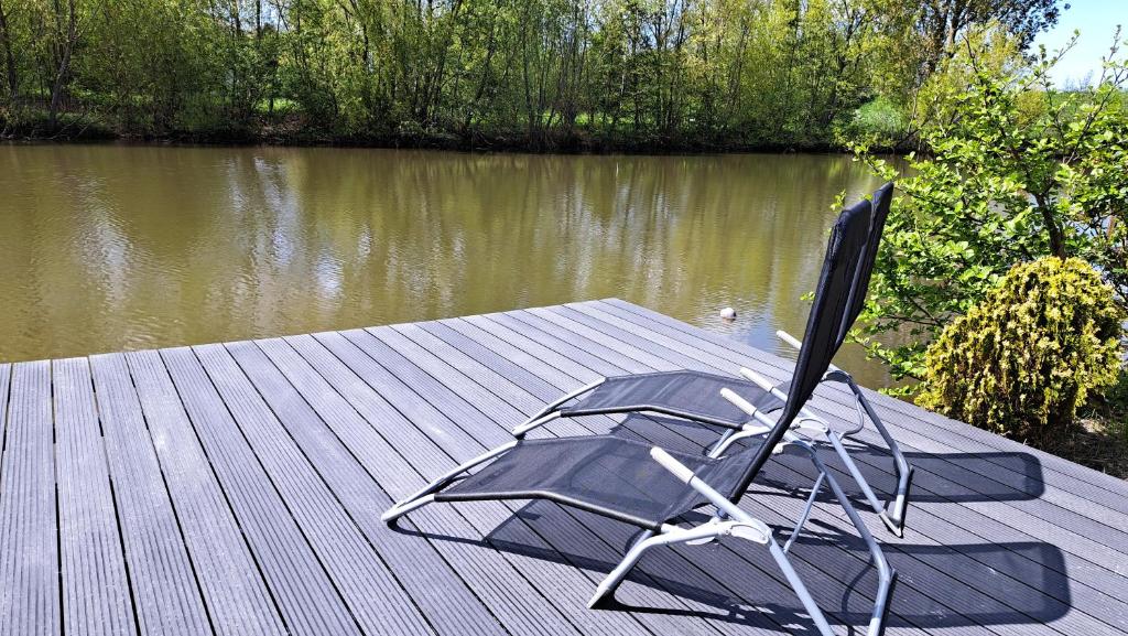 una silla sentada en un muelle junto a un lago en Het witte chalet aan het water van monumentaal fort, en Ooltgensplaat