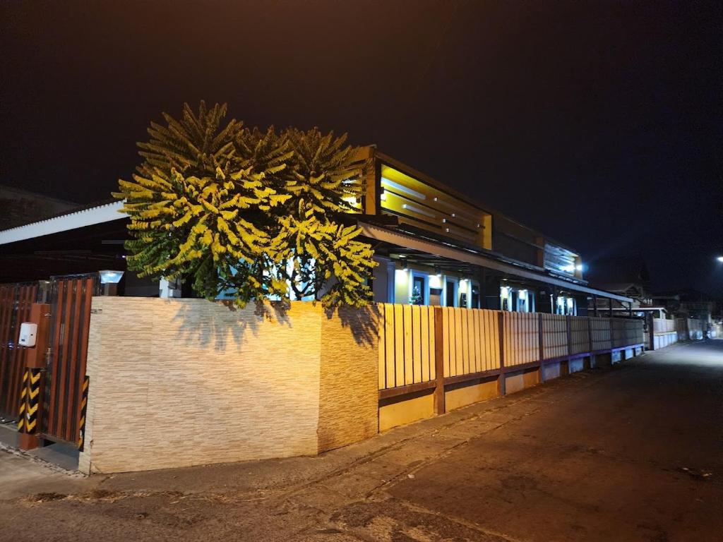 un edificio con un árbol al lado de una valla por la noche en ONE DD HOMES en Udon Thani