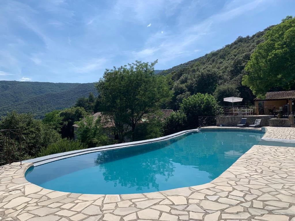 a swimming pool with a mountain in the background at Gîte Framboisier au Château des Pauses in Saint-André-de-Majencoules