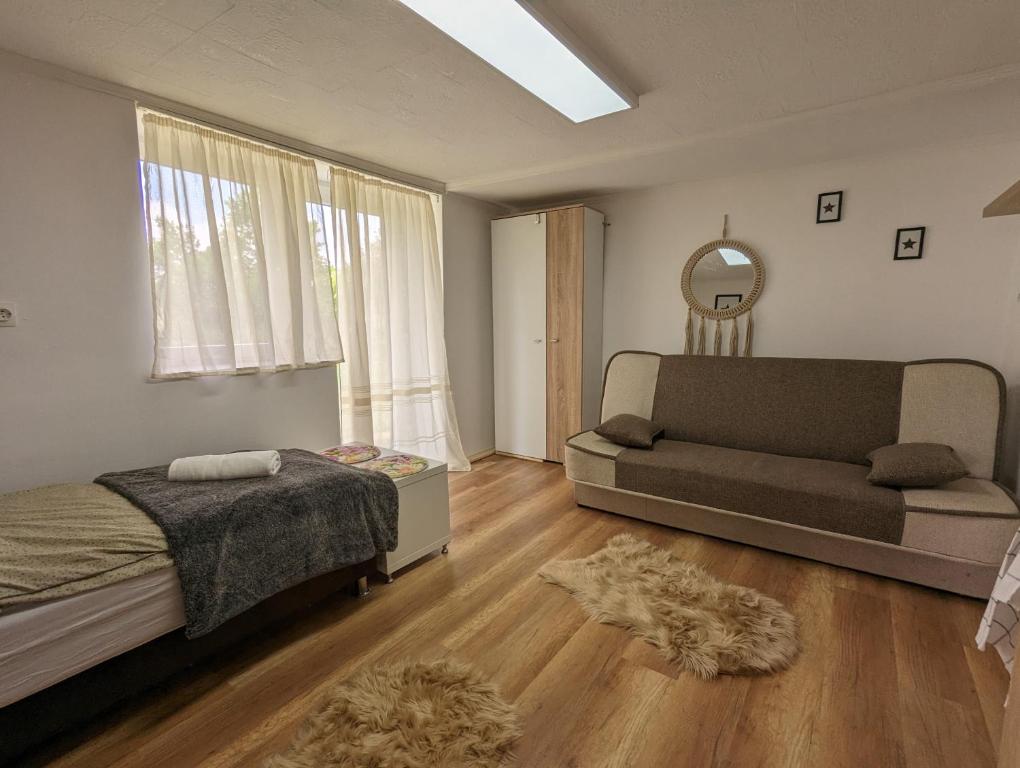 1 dormitorio con cama, sofá y espejo en Sweety-Apartman en Mátészalka