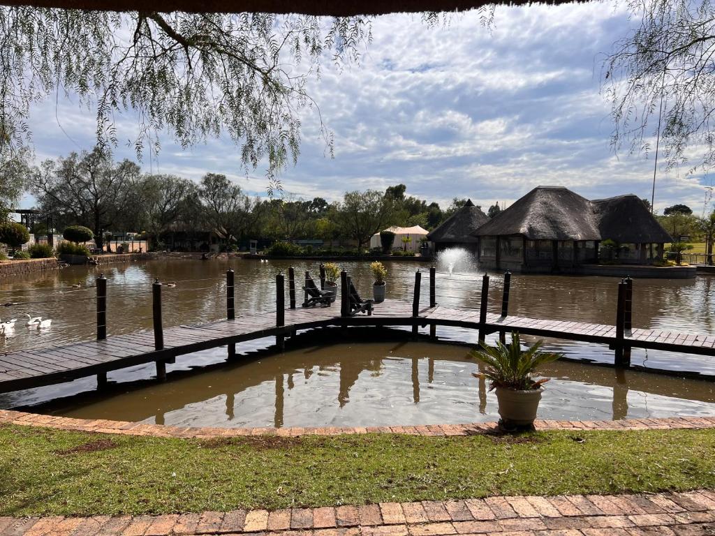 a body of water with a bridge and a house at Swan Lake Suites in Benoni