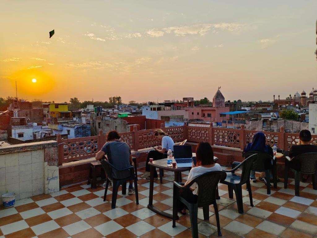 een groep mensen die aan tafel zitten op een balkon met uitzicht op een stad bij Hotel India inn in Agra