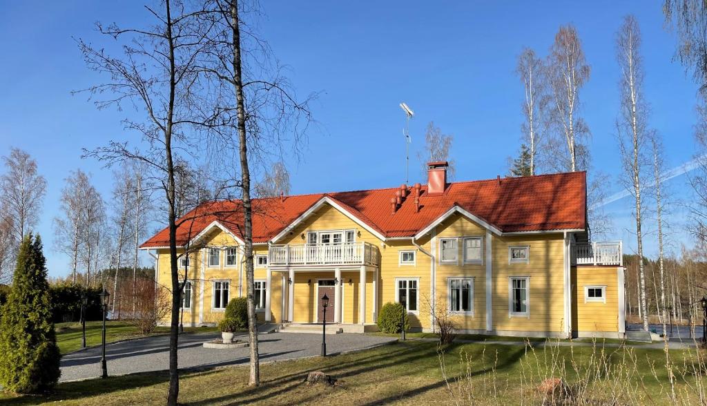 a large yellow house with a red roof at Lossirannan Kartano in Huutotöyry