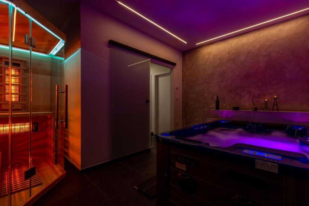 ein Badezimmer mit einer großen Badewanne mit violetter Beleuchtung in der Unterkunft Luxury Hedone Apartment near the Bridge with Private SPA Zone in Zadar