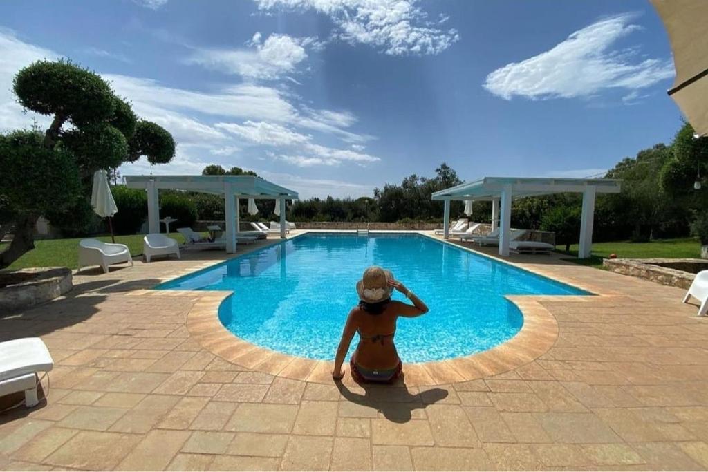 a woman sitting in front of a swimming pool at Casetta Letizia in Ostuni