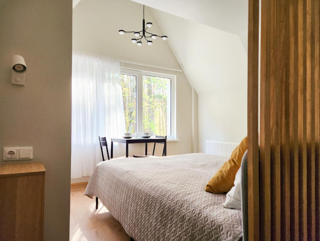 ein Schlafzimmer mit einem Bett und einem Tisch mit einem Fenster in der Unterkunft Pušynas in Birštonas