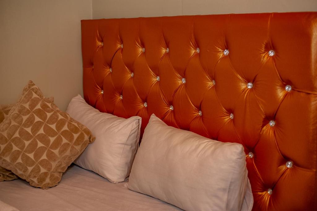 a bed with white pillows and an orange headboard at 66 Anglers in Richards Bay
